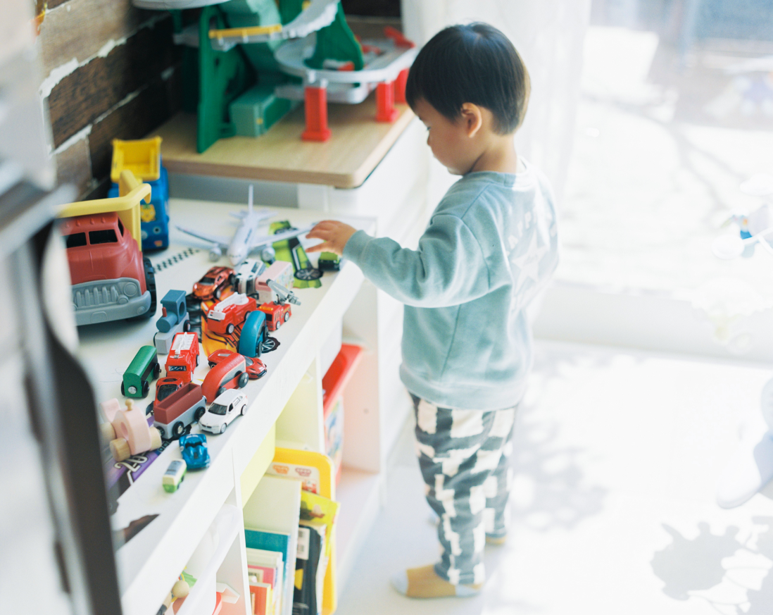 のりもののおもちゃに手をのばす男の子。