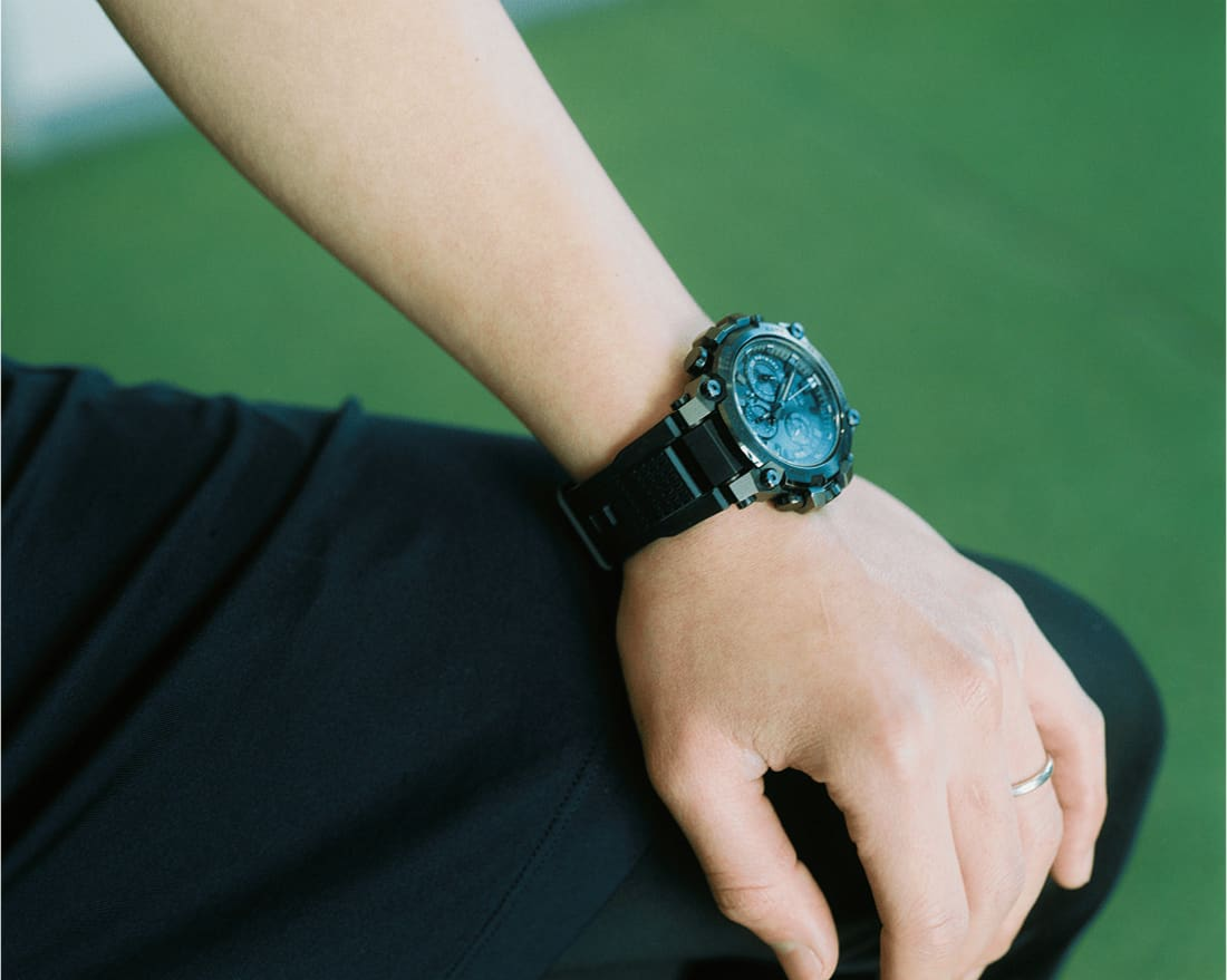 座った姿勢で腕時計を見せる下平さんの手元。