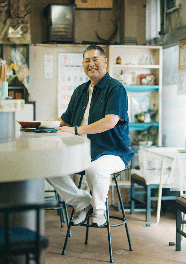  飲食店の店内に座る森田仁さん