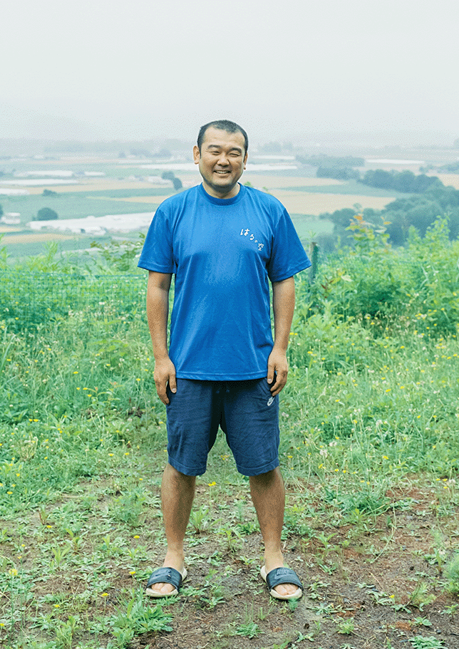 美瑛の自然を背景に立つ春日晴樹さん