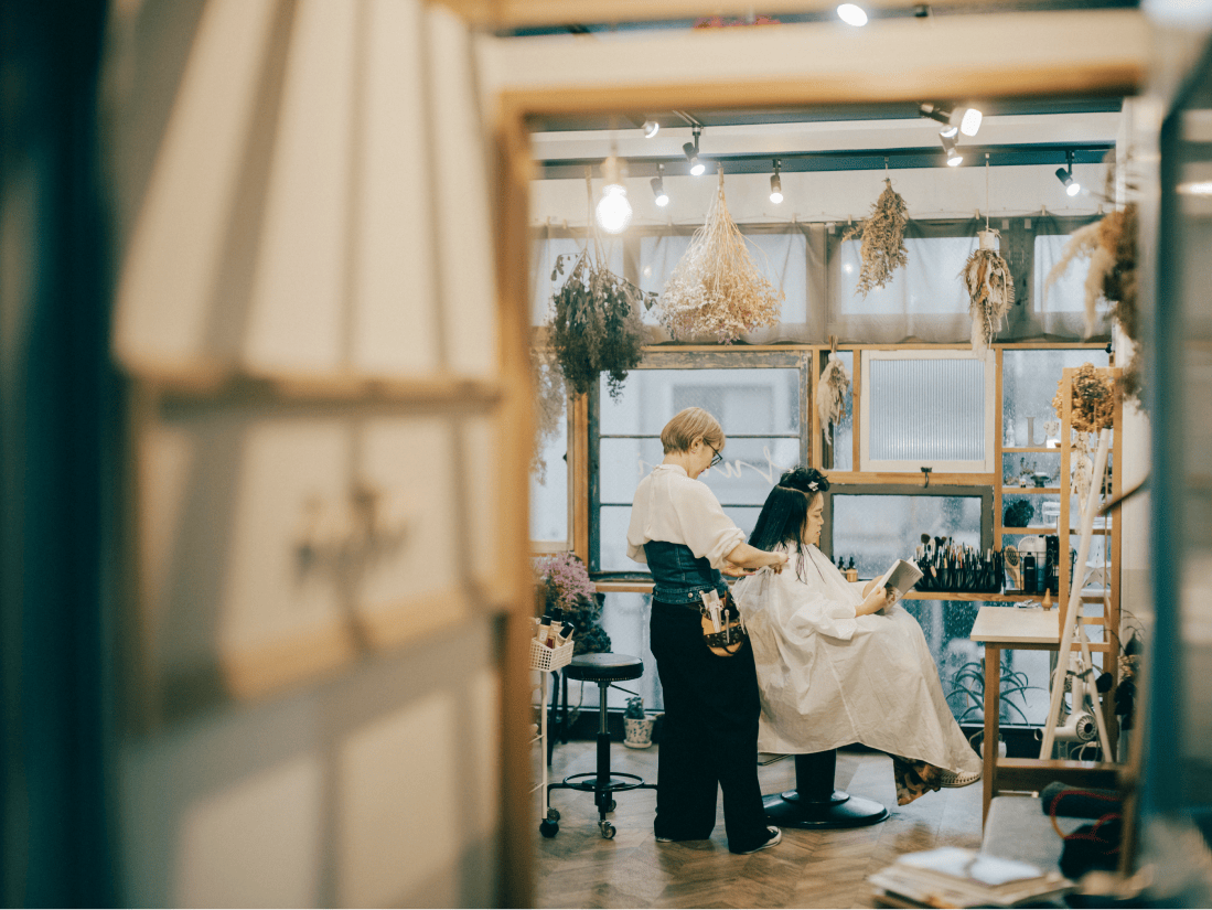 様々なお花が飾られた部屋で髪を切られている女性