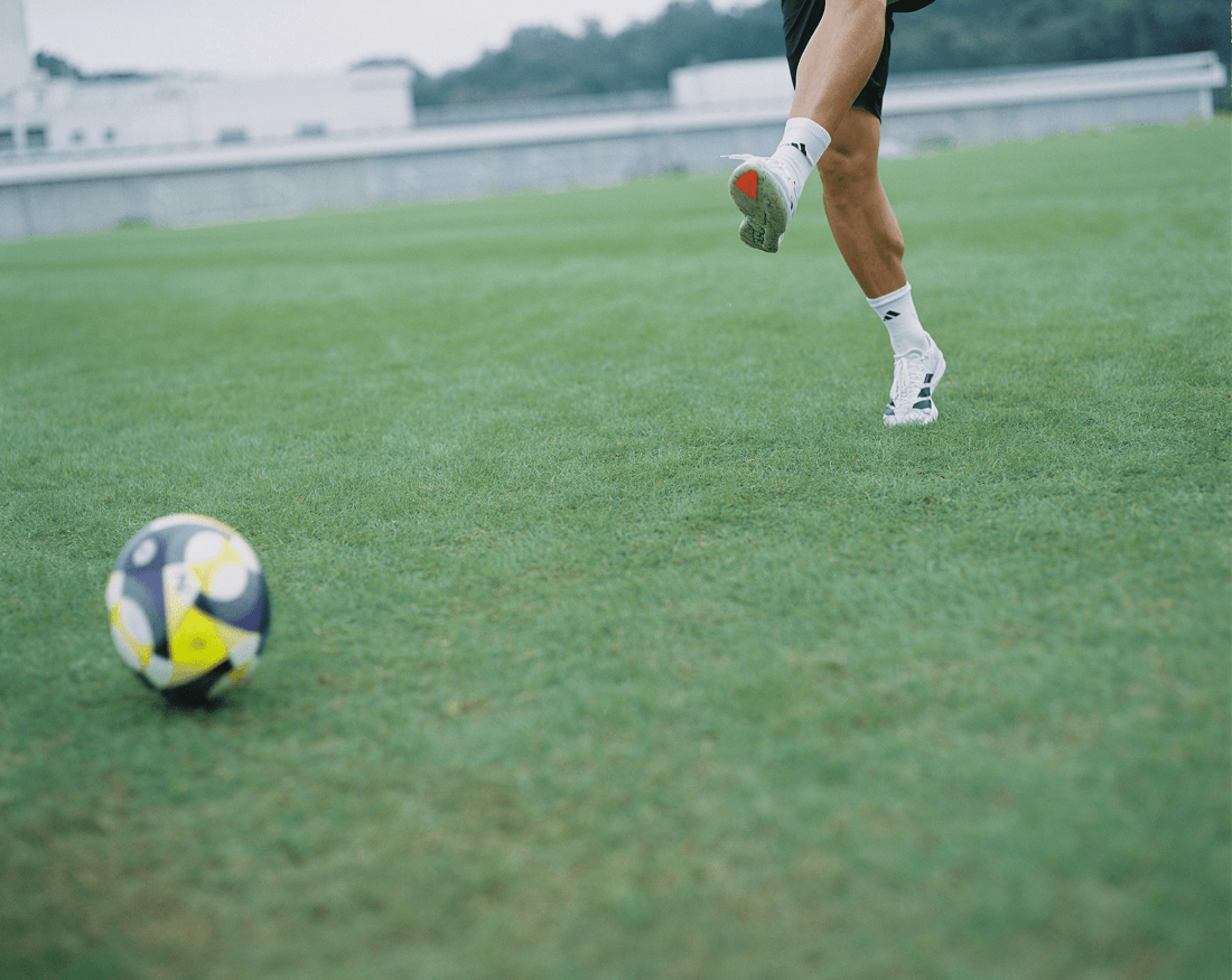 芝生の上に置かれたサッカーボールと選手の足元