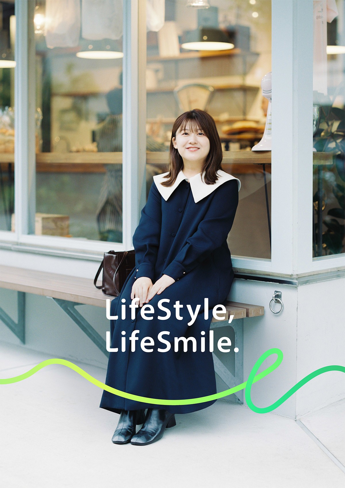 ガラス張りの店舗前のベンチに座る尾崎里紗のポートレートガラス張りの店舗前のベンチに座る尾崎里紗のポートレート