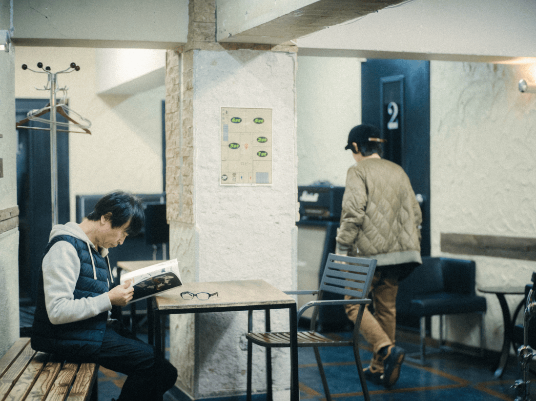 本を読んでいる男性とその前を通り過ぎた男性。