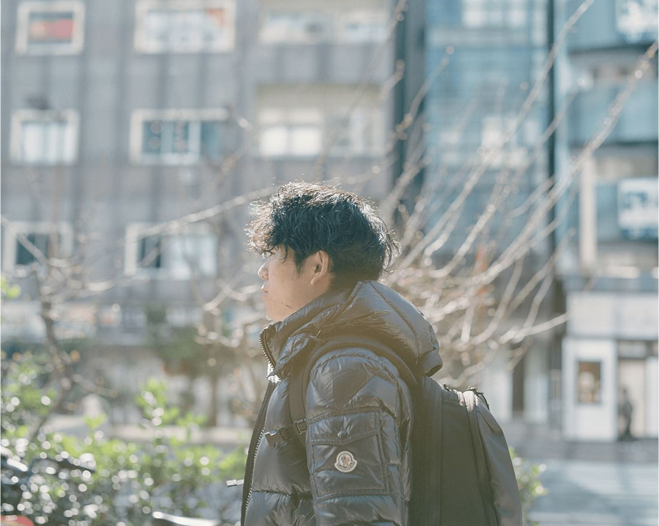 冬の街を歩く男性。陽射しが差し込むなか、真剣な表情で前を見つめている。