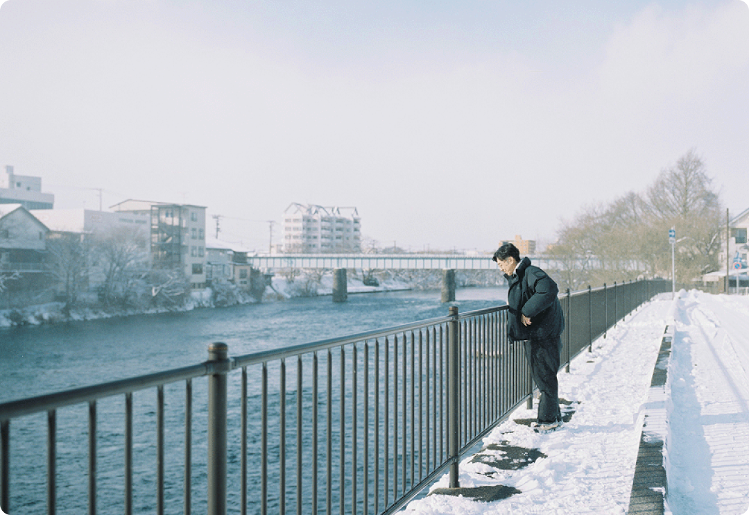 雪が積もる川沿いを歩く天津木村卓寛