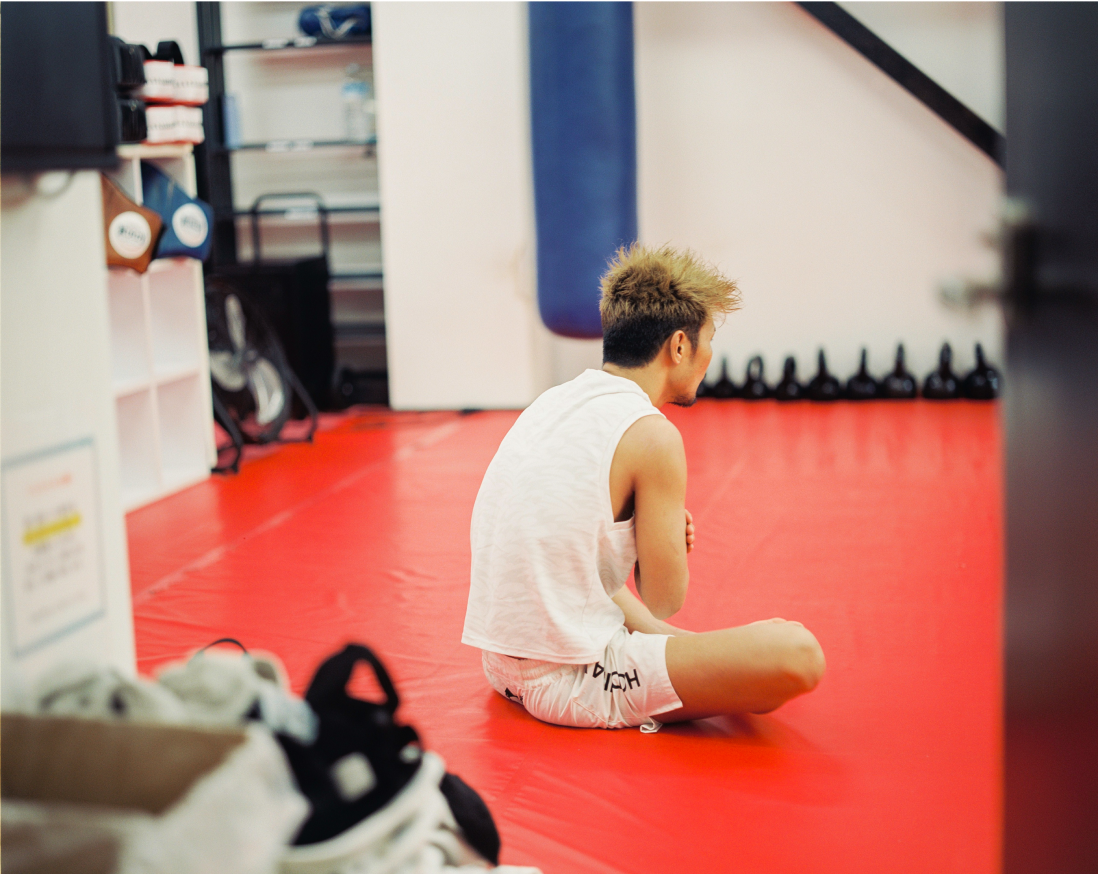 赤いマットに座っている男性。