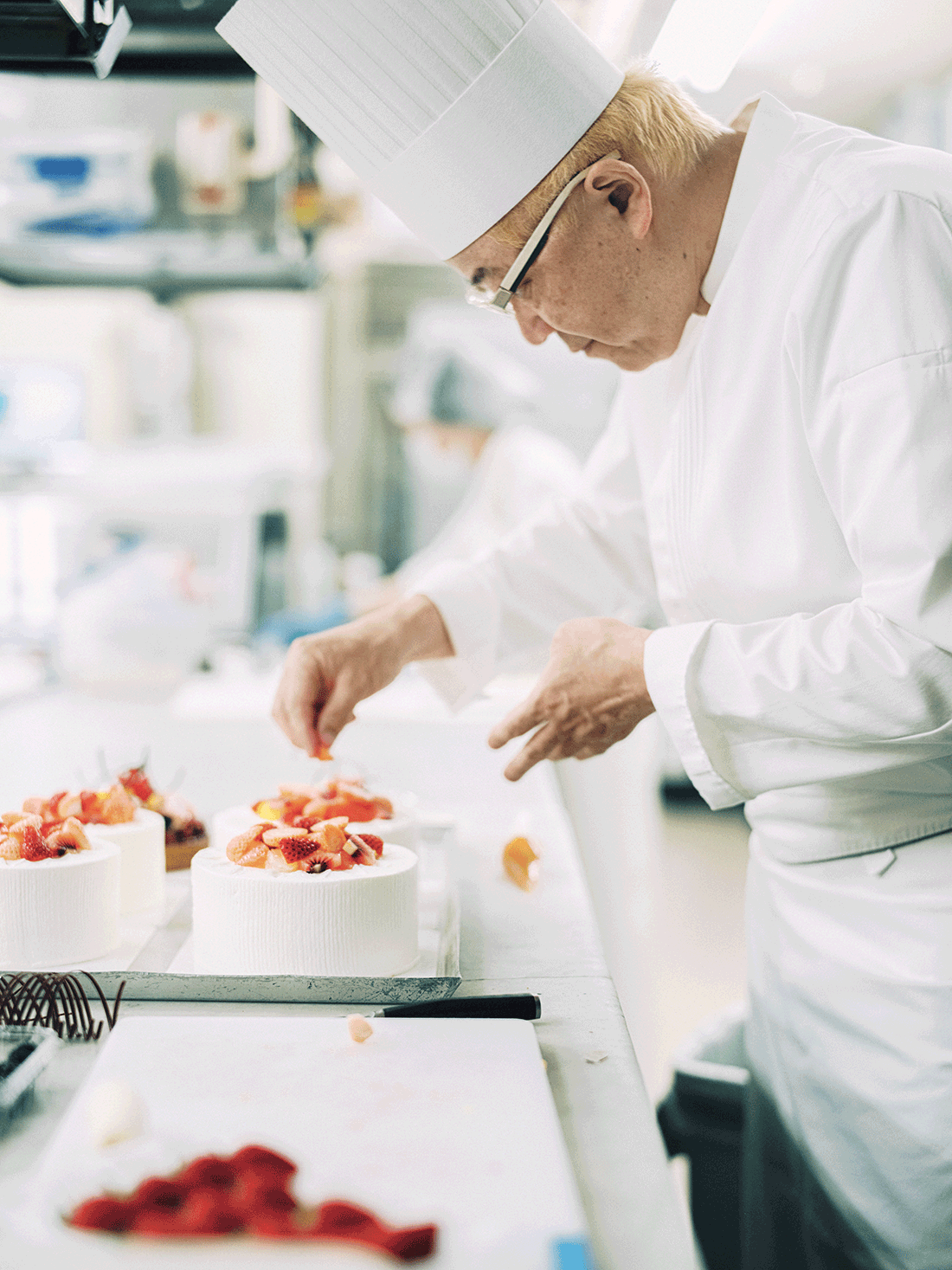 パティシエ・辻󠄀口博啓さんが、ホールケーキにいちごを飾り付けている。
