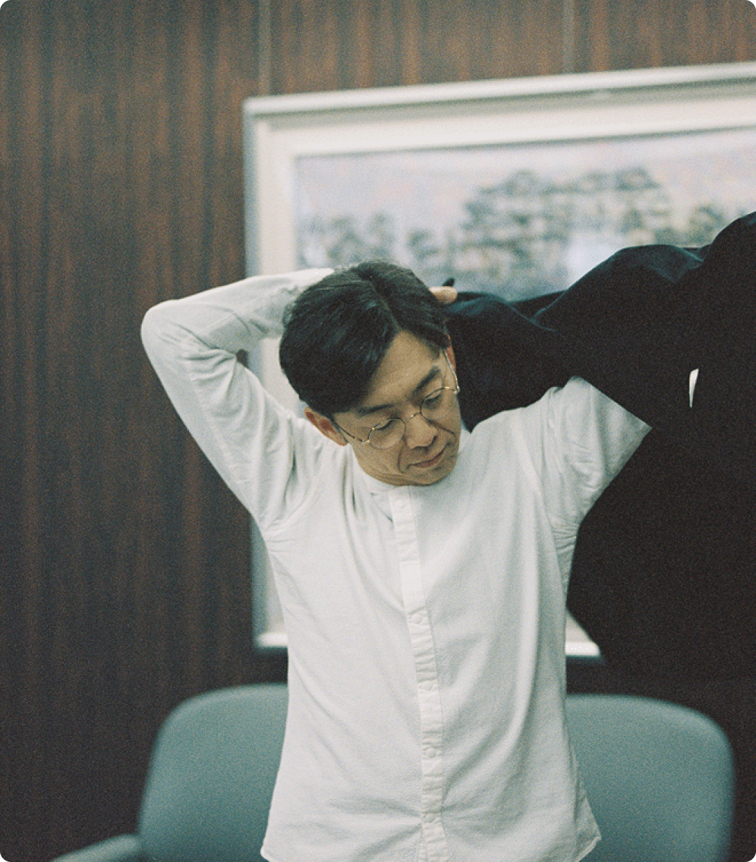 室内でジャケットを羽織る天津木村卓寛