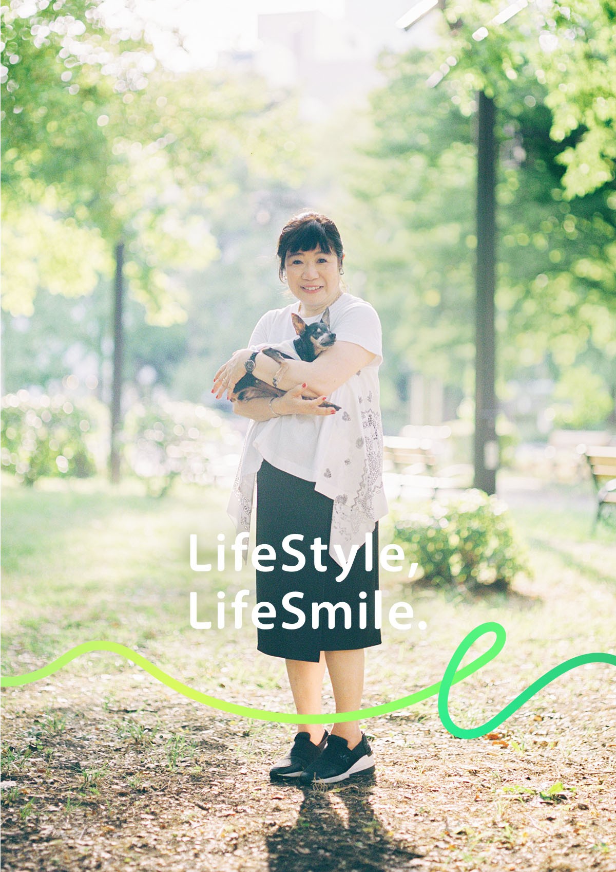 放送作家・芸能コラムニスト 山田 美保子が笑顔で愛犬を抱えている写真。