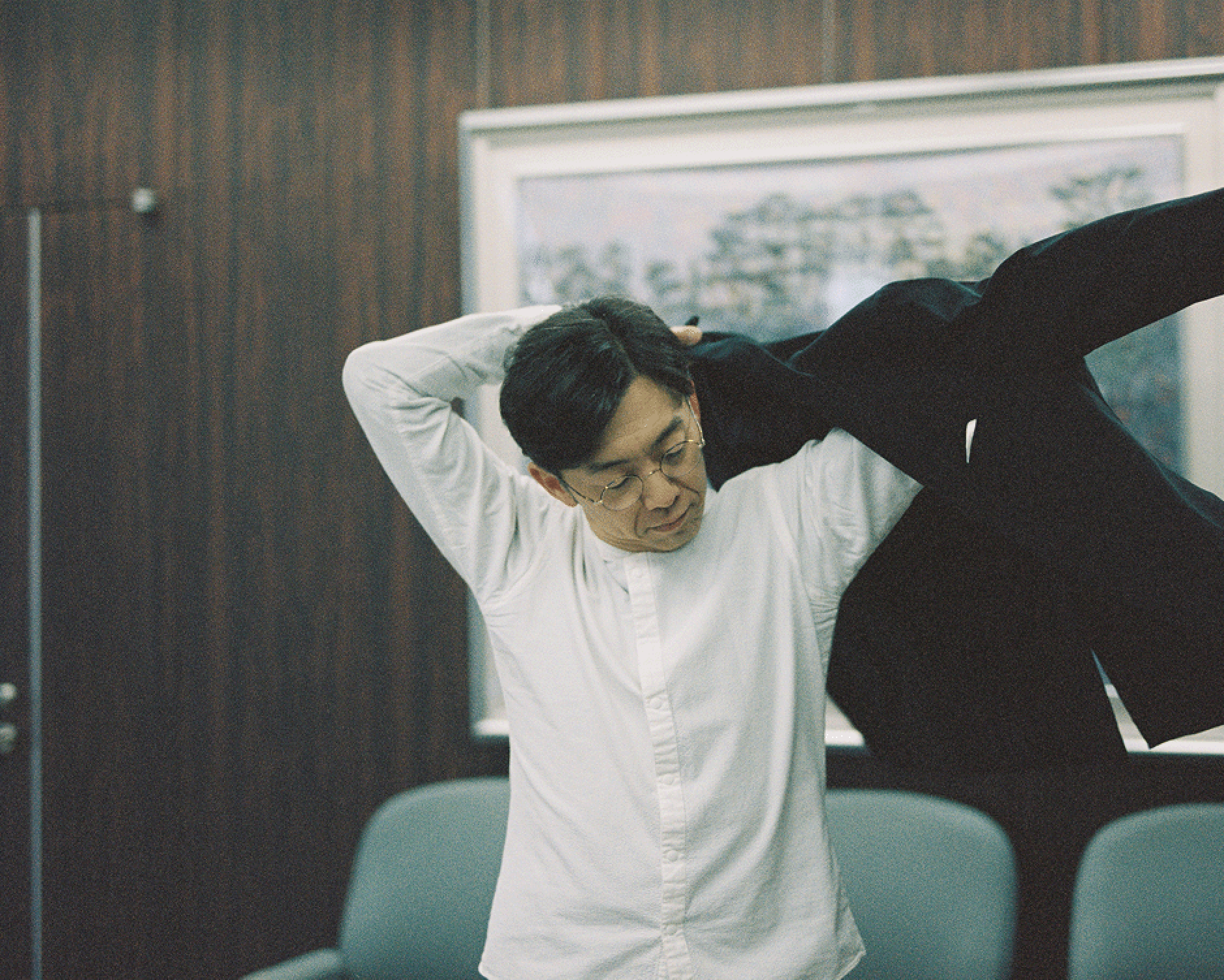 室内でジャケットを羽織る天津木村卓寛