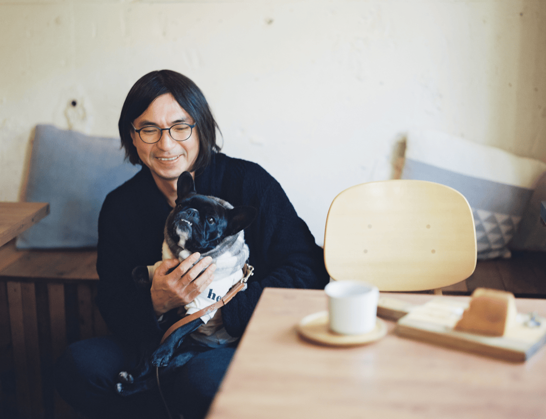 犬を抱えて笑顔の男性。