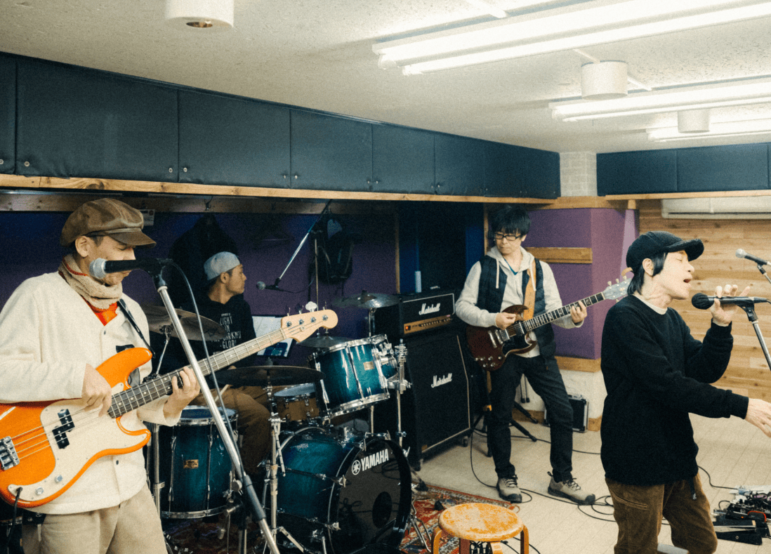 4人の男性がスタジオで練習している様子。