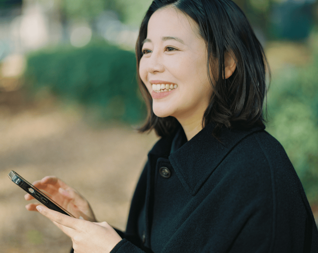 笑顔でスマートフォンを持った女性。