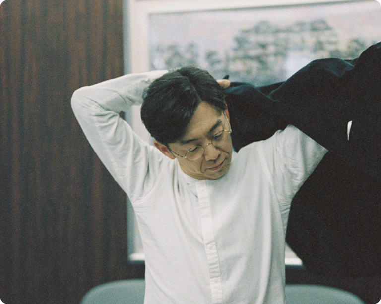 室内でジャケットを羽織る天津木村卓寛