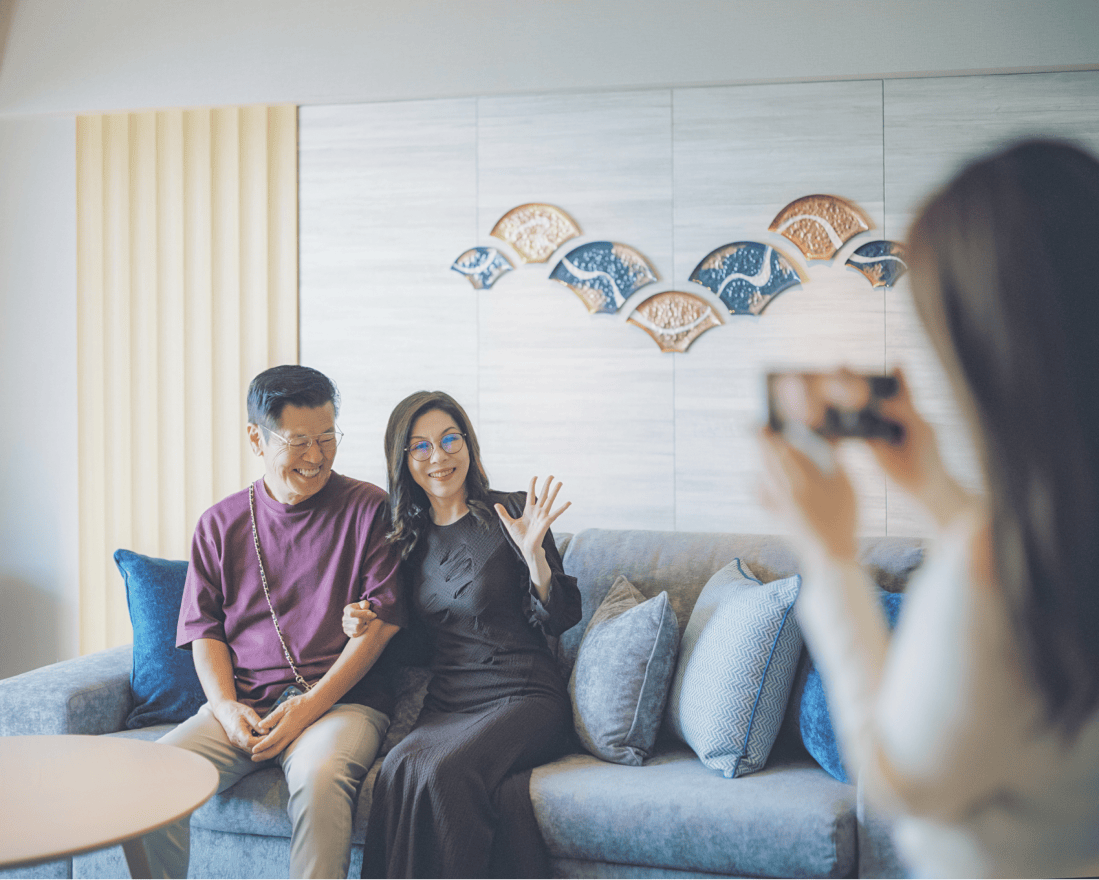 ソファーの上で被写体になっている笑顔の男女。目線の先