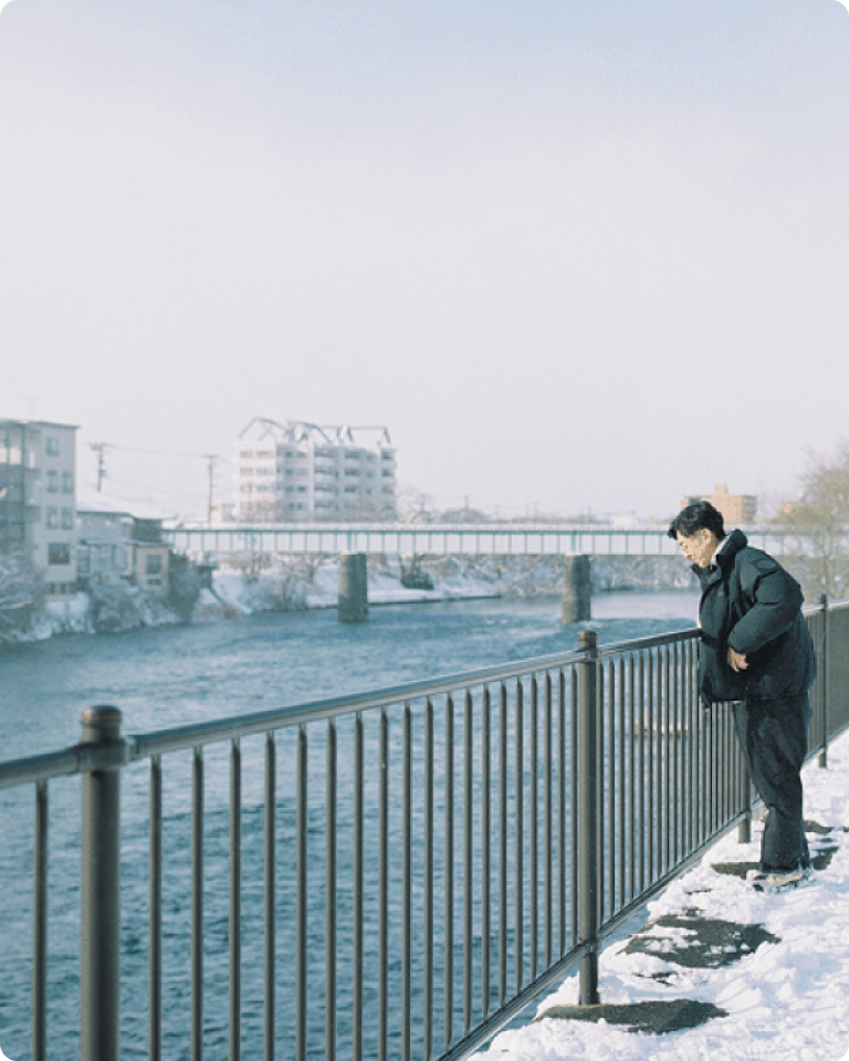 雪が積もる川沿いを歩く天津木村卓寛