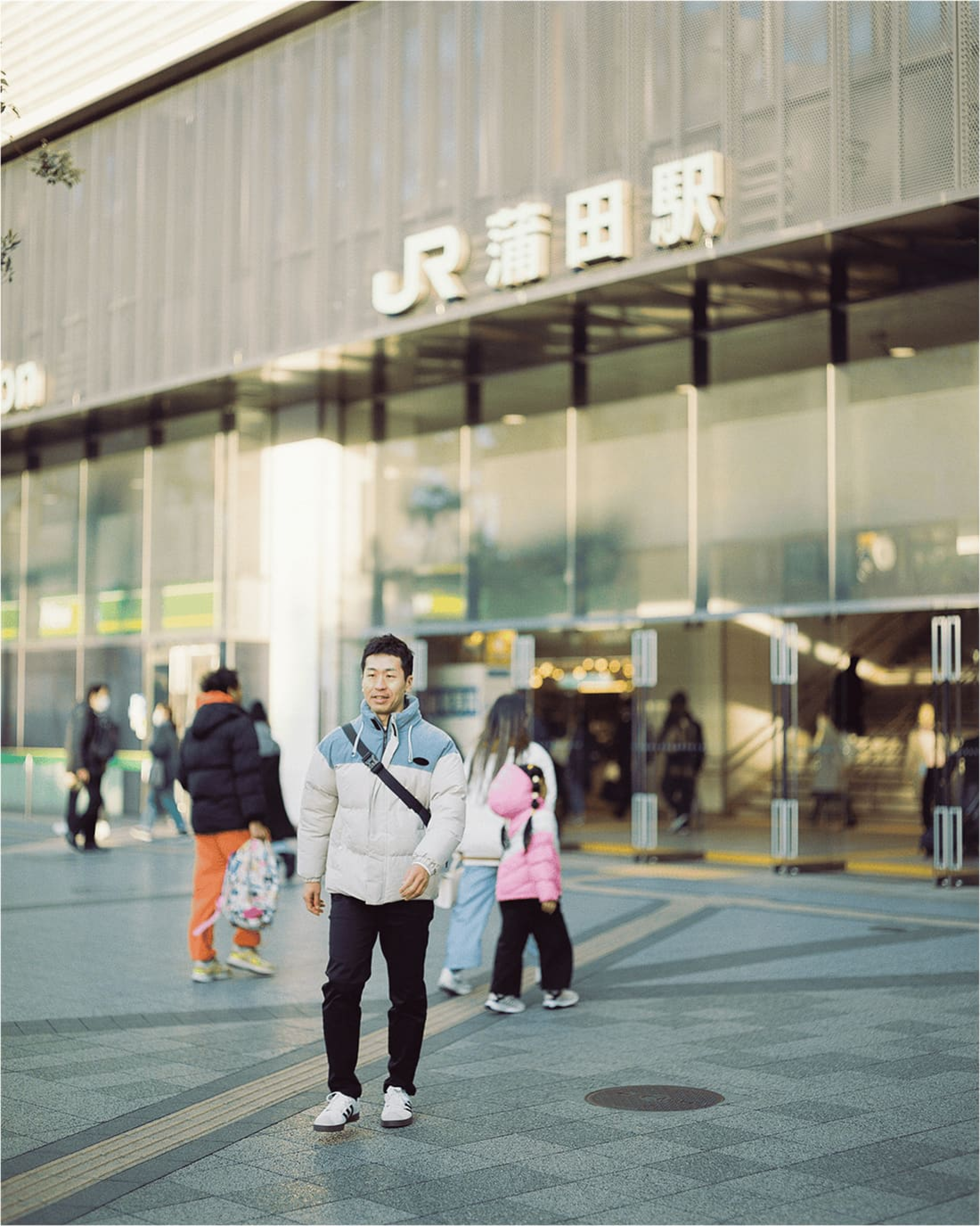 JR蒲田駅の前を歩く男性。冬の装いで穏やかな表情を見せている。